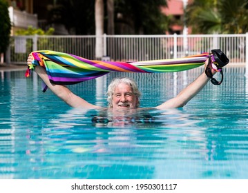 Portrait Of A Smiling Relaxed Senior Man In The Swimming Pool With A Colorful Towel In The Hands - Active Elderly Enjoying Healthy Lifestyle