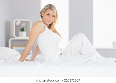 Portrait of a smiling relaxed young woman sitting in bed at home