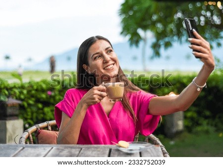 Portrait of smiling russian woman drinking hot capuccino and taking a selfie