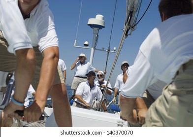 Portrait of a smiling sailor with crew on the sailboat deck against clear sky