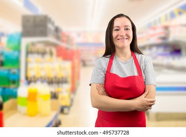portrait of smiling saleswoman standing and looking at the supermarket with crossing arms - Powered by Shutterstock