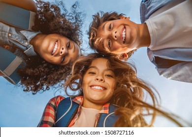 Portrait Of Smiling School Kids Standing In Cecrle At School Yard With Look In Camera