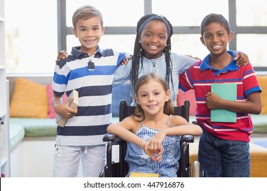 Portrait of smiling school kids standing with arm around in library at school - Powered by Shutterstock