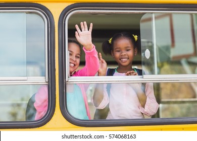 Portrait Of Smiling School Kids Waving Hand From Bus