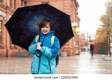 Portrait Of A Smiling Schoolboy With An Umbrella On A Rainy Day Outside