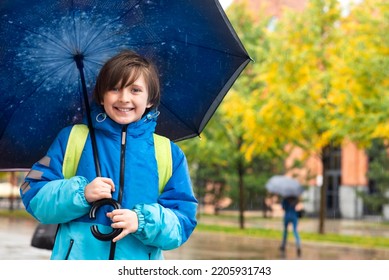 Portrait Of A Smiling Schoolboy With An Umbrella On A Rainy Day Outside