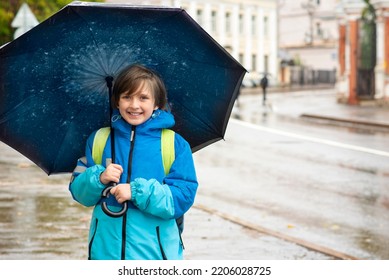 Portrait Of A Smiling Schoolboy With An Umbrella On A Rainy Day Outside