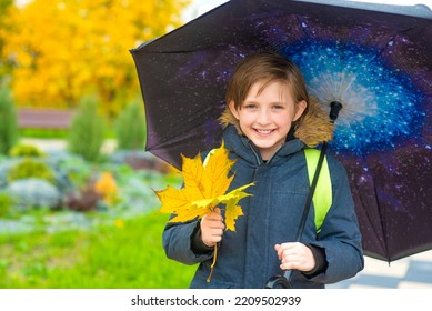 Portrait Of A Smiling Schoolboy With An Umbrella On A Rainy Day Outside