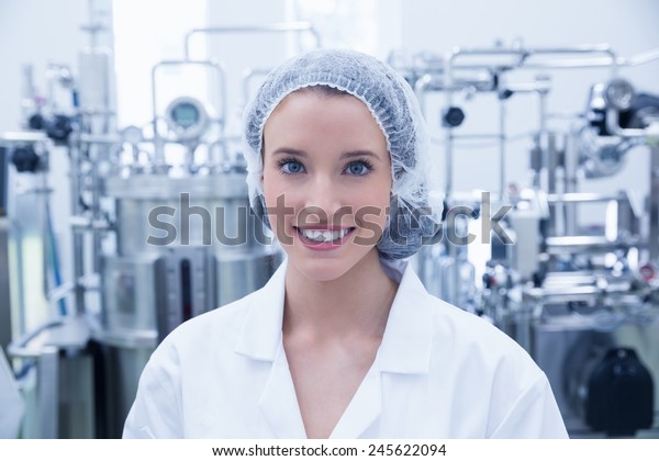 Portrait of a smiling scientist wearing hair net\
in the factory