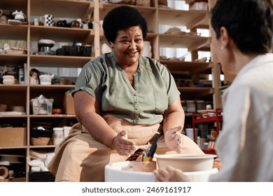 Portrait of smiling senior African American woman enjoying pottery class in cozy studio lit by sunlight copy space - Powered by Shutterstock