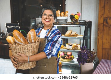 Portrait of a smiling senior Asian barista, hands holding bread basket with promotion sign welcoming the customer in a cozy coffee shop.  Small business owner, family manage. - Powered by Shutterstock