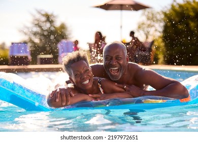 Portrait Of Smiling Senior Couple On Summer Holiday Relaxing In Swimming Pool On Inflatable - Powered by Shutterstock