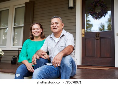Portrait Of Smiling Senior Couple Sitting In Front Of Their Home