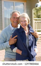 Portrait Of Smiling Senior Couple Standing By Beach House