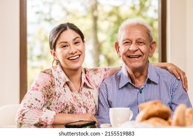 Portrait of a smiling senior father with his beautiful older daughter looking at the camera, happy mature man and young beautiful latin woman.