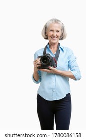 Portrait Of Smiling Senior Female Photographer With Camera Against White Background