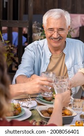 Portrait Of Smiling Senior Man Clinking Glasses With Members Of His Family At Birthday Dinner