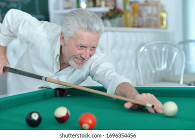 Portrait Of Smiling Senior Man Playing Billiard At Home