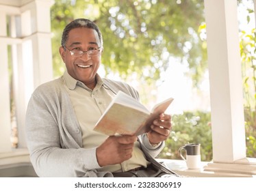 Portrait of smiling senior man reading book on porch - Powered by Shutterstock