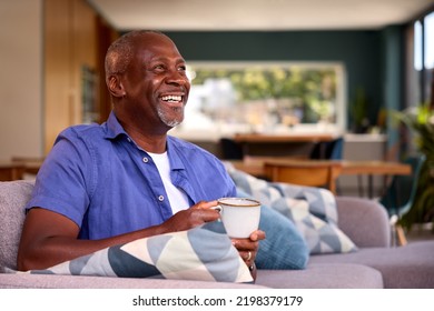 Portrait Of Smiling Senior Man Relaxing On Sofa At Home Holding Hot Drink - Powered by Shutterstock