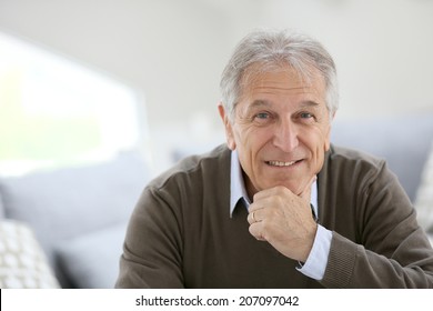 Portrait of smiling senior man sitting on sofa at home