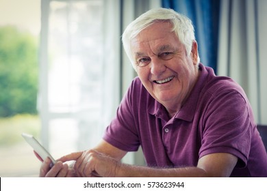 Portrait Of Smiling Senior Man Using Mobile Phone At Home