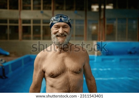 Portrait of smiling senior man with wet body in swimming pool looking at camera