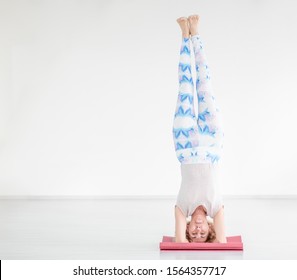 Portrait of a smiling senior woman doing advanced yoga or pilates. Supported headstand, salamba sirsasana. Empty space for text - Powered by Shutterstock