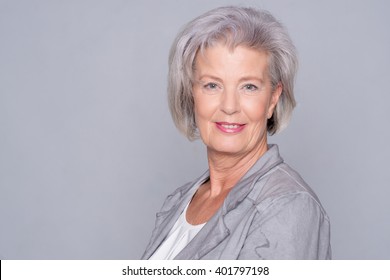 Portrait of a smiling senior woman in front of gray background - Shutterstock ID 401797198