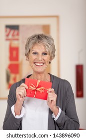 Portrait Of A Smiling Senior Woman Holding Gift Coupon At Home