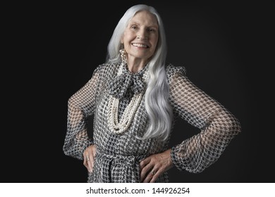 Portrait Of A Smiling Senior Woman With Long Gray Hair Against Black Background