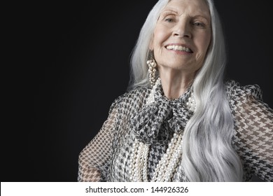 Portrait Of A Smiling Senior Woman With Long Gray Hair Against Black Background