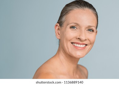 Portrait of a smiling senior woman looking at camera. Closeup face of mature woman after spa treatment isolated over grey background. Anti-aging concept.