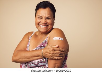 Portrait Of A Smiling Senior Woman Receiving A Vaccine. Mature Woman Showing Her Arm With Bandage After Vaccination.