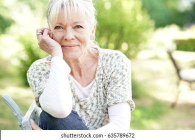 Portrait Of Smiling Senior Woman Relaxing In Garden