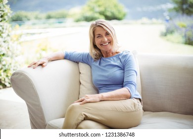 Portrait of smiling senior woman sitting on sofa in living room at home