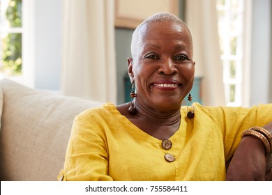 Portrait Of Smiling Senior Woman Sitting On Sofa At Home