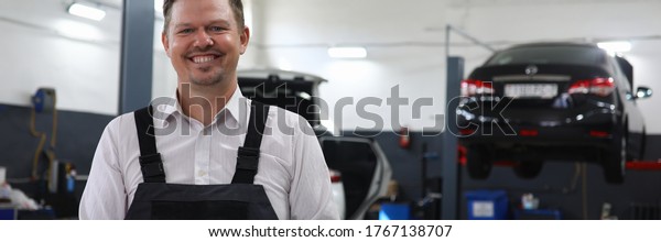 Portrait of smiling service\
station worker filling checklist paper on clipboard. Happy mechanic\
in uniform in garage. Car maintenance and restoration workshop\
concept