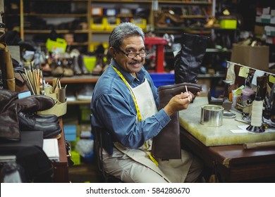 Portrait of smiling shoemaker applying glue on shoe in workshop - Powered by Shutterstock