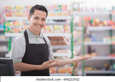 Portrait Of A Smiling Shopkeeper In A Grocery Store Welcoming Customer