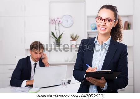 portrait of smiling spanish business woman holding cardboard in office
