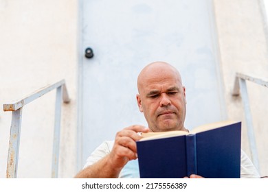 Portrait Smiling Spanish Middle-aged Man, Reading An Interesting Book With A Serious Face