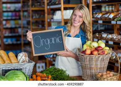 Portrait of smiling staff holding organic sign board in organic section of super market - Powered by Shutterstock