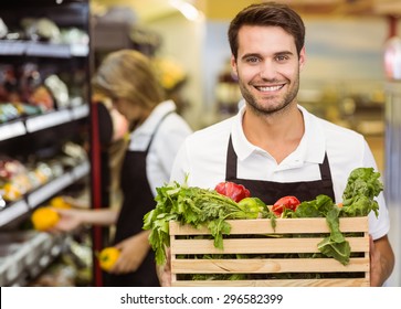 Portrait of a smiling staff man holding a box of fresh vegetables at supermarket - Powered by Shutterstock
