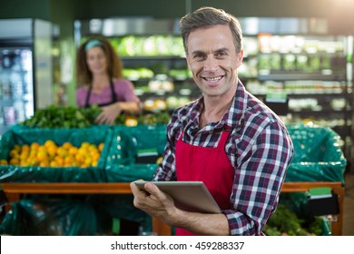 Portrait of smiling staff using digital tablet in organic section of supermarket - Powered by Shutterstock