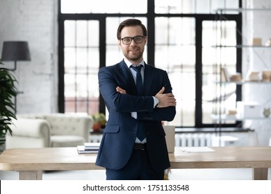 Portrait Of Smiling Successful Caucasian Businessman In Formal Suit Glasses Stand Posing In Modern Office, Happy Young Male Boss Or CEO Look At Camera, Show Confidence And Power, Leadership Concept