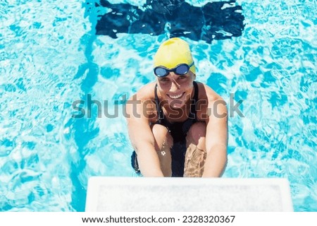 Portrait of smiling swimmer poised at starting block