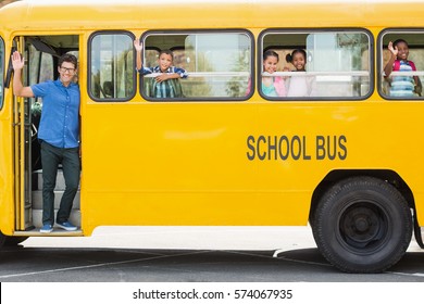 Portrait Of Smiling Teacher And Kids Waving Hand From Bus