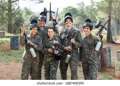 Portrait of smiling team of paintball players with marker guns ready for game outdoors