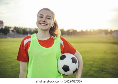 Portrait Of A Smiling Teen Girl Football Player With A Soccer Ball At Sunset